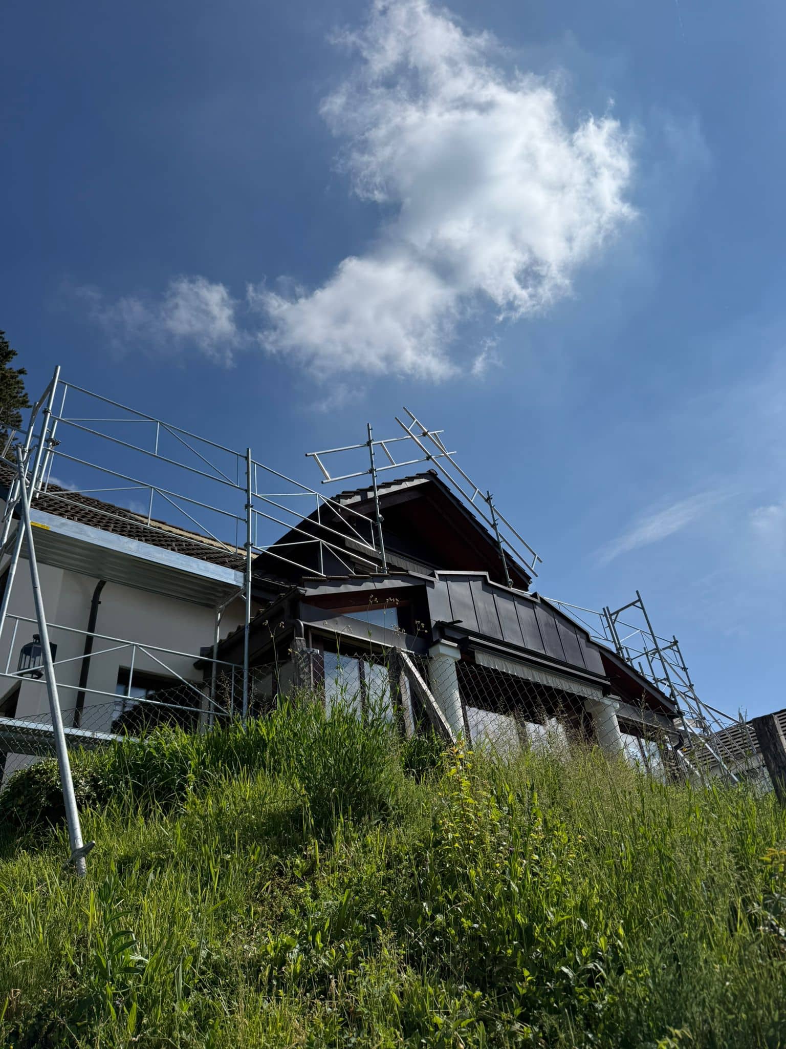 Schutz- und Dachfanggerüst von Elian Gerüstbau rund um ein Steildach eines Schweizer Chalets